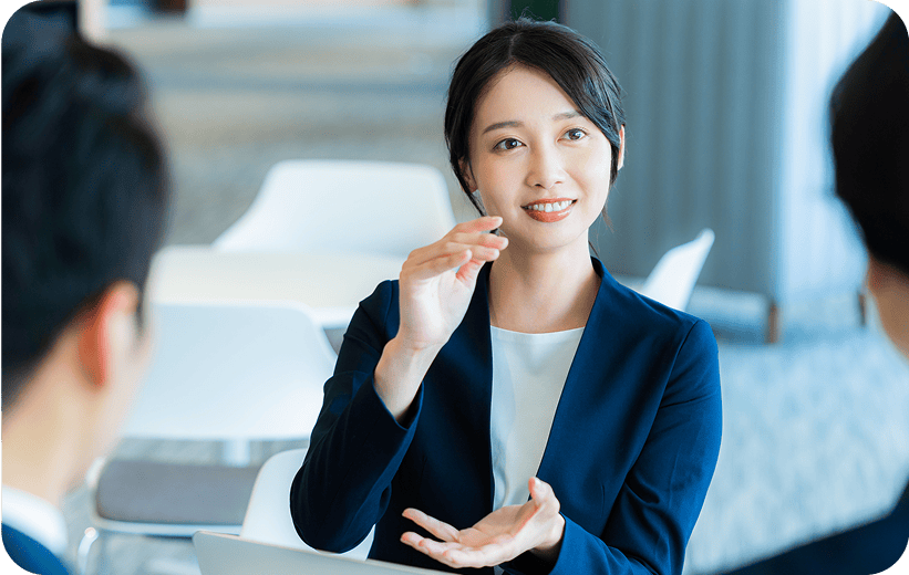 スーツを着た女性が男性2名と話をしている