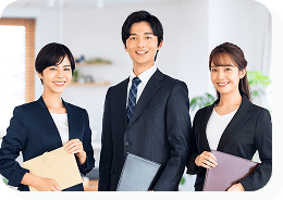 スーツを着た女性2名と男性1名が正面を見て微笑んでいる