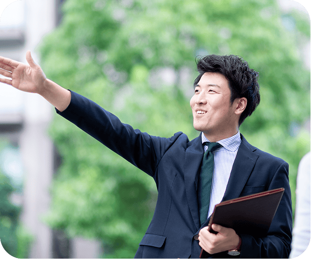 スーツを着た男性が外でお客さんに案内している